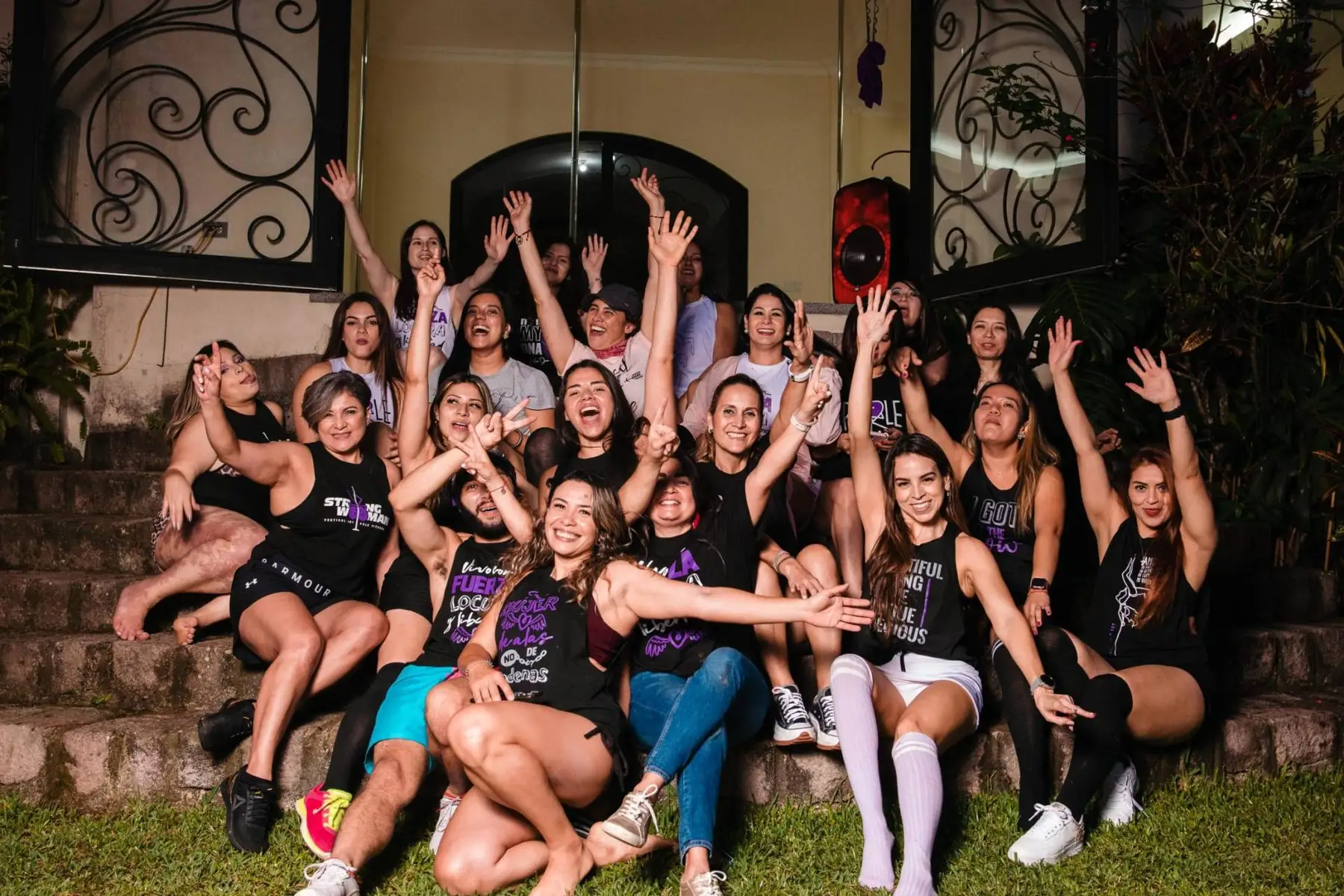 Grupo grande de mujeres con camisetas de Vertical Art celebrando en una escalinata de noche