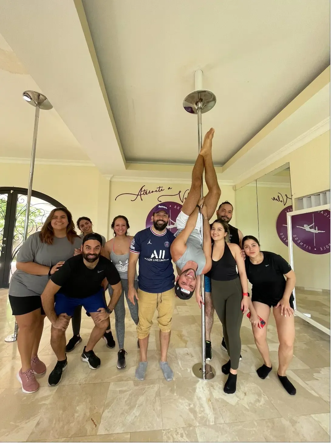 Grupo mixto en un estudio con barras, una persona invertida en la barra